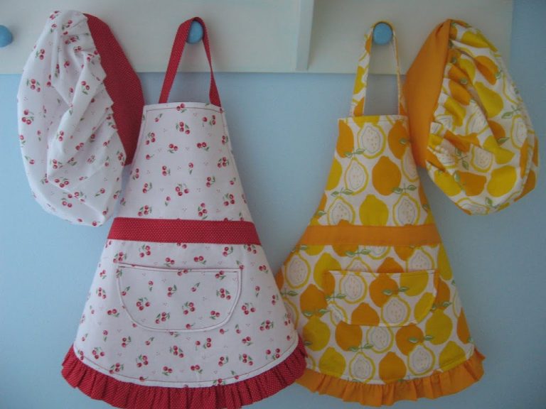 Two child's aprons and hats hand on coat hangers