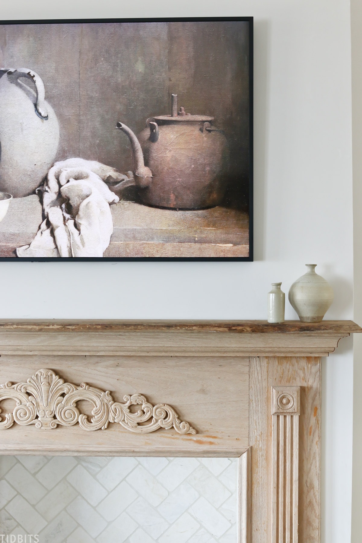 two pieces of pottery placed on faux mantel with antique painting on wall above mantel