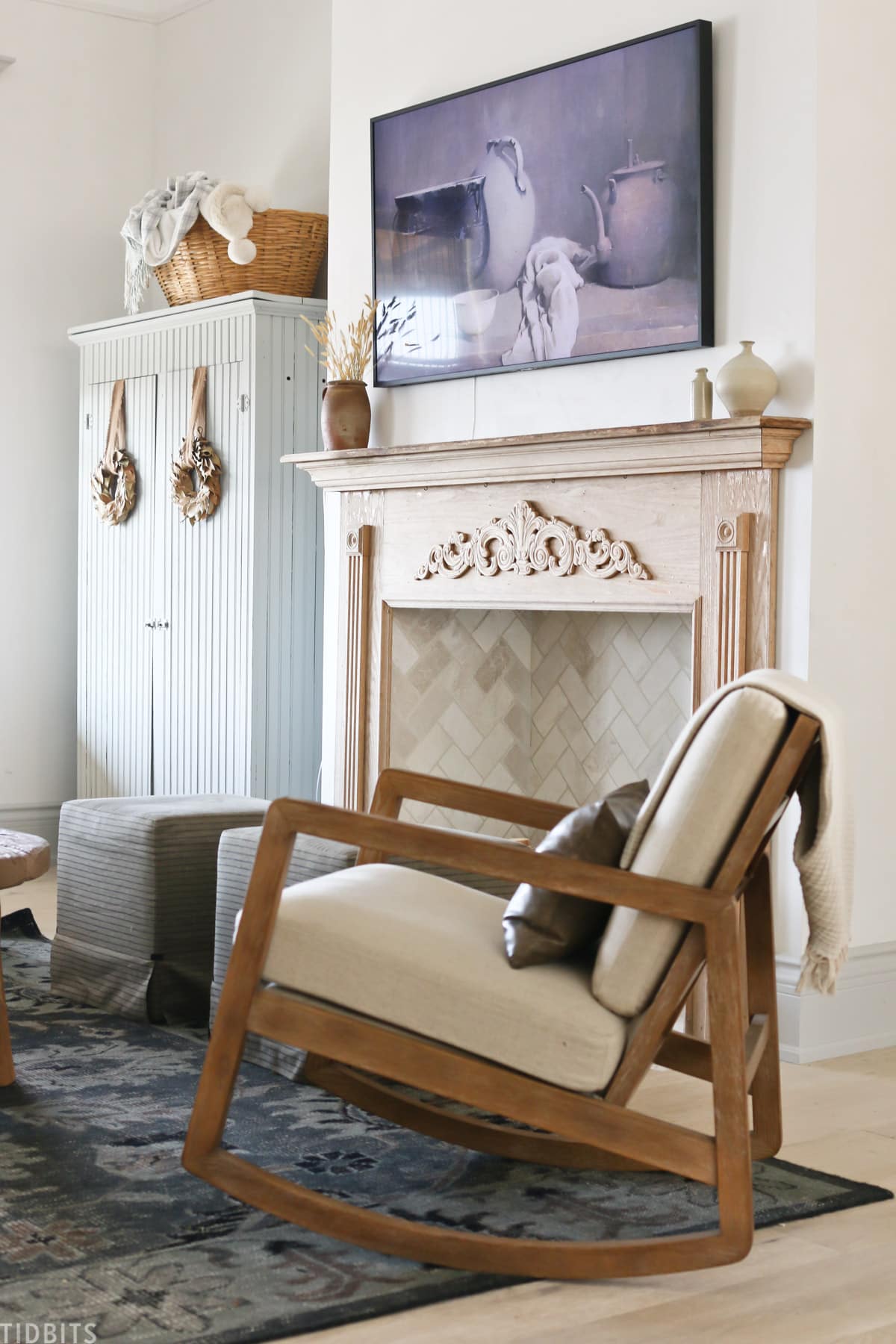 wooden rocking chair in front of faux fireplace with home decor items placed throughout living room