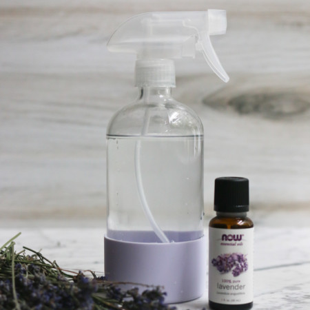 A bottle of essential oils, lavender and a linen spray sit next to each other