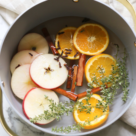 A simmer pot of stove top potpourri with apples, oranges, cinnamon, cloves and lemon thyme