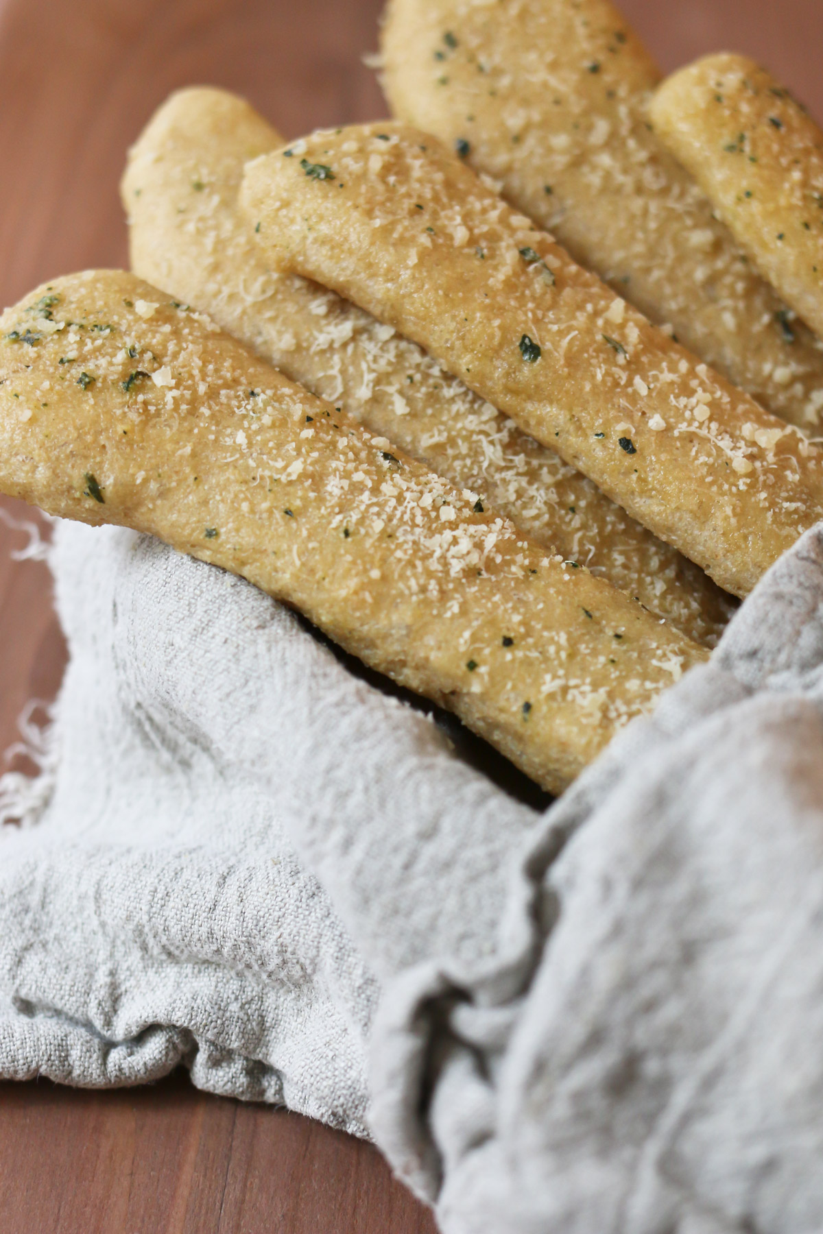 A bundle of whole wheat breadsticks is wrapped in a tea towel
