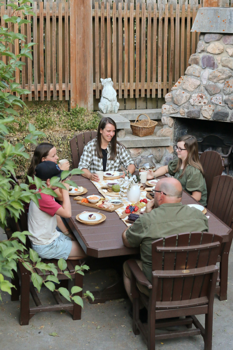 A family sits around an outdoor table enjoying summer charcuterie boards