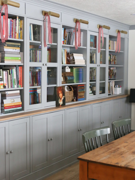 Bookcases with light fixtures are adorned with red gingham ribbon as entryway decor