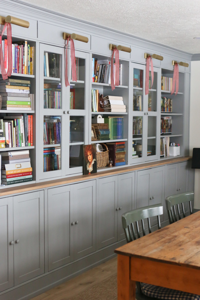 Bookcases with light fixtures are adorned with red gingham ribbon as entryway decor
