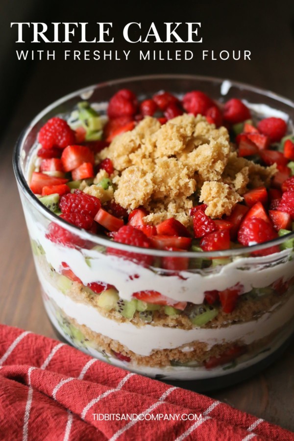 A layered trifle cake with whipped cream and fruit in a glass bowl