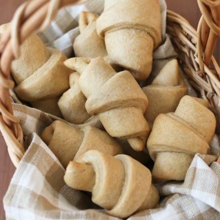 A linen-lined basket holds homemade crescent rolls made from a recipe using freshly milled flour
