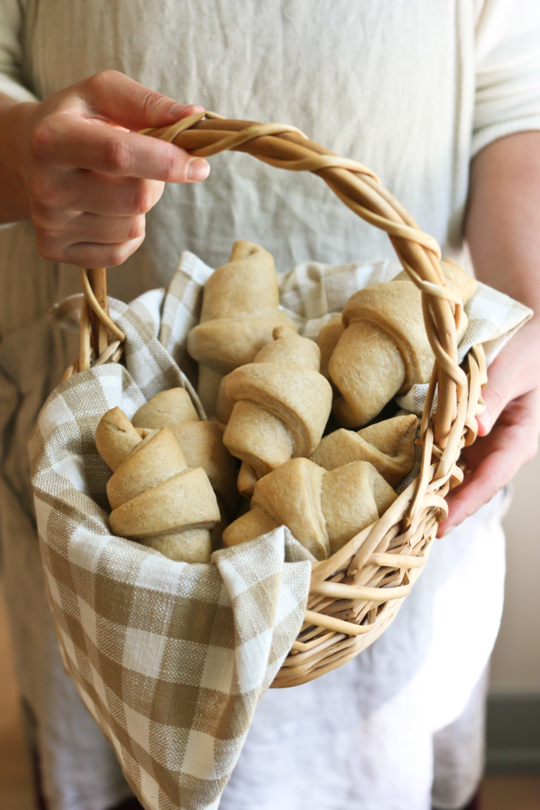 Someone holds a basket of homemade crescent rolls made with freshly milled flour