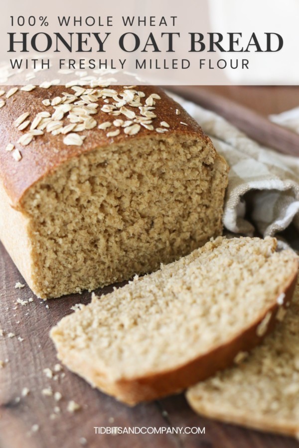 A loaf of homemade honey oat loaf bread made with fresh milled flour is sliced on a cutting board