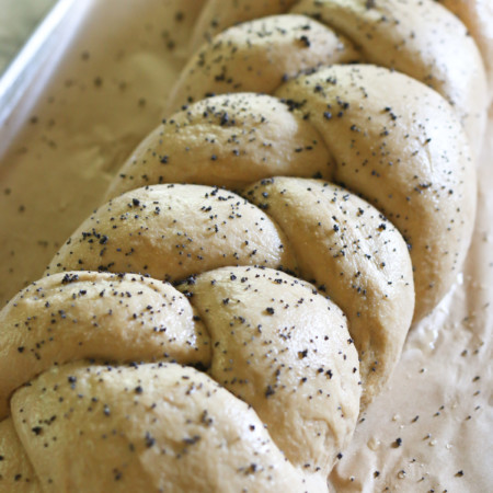 A freshly baked loaf of traditional challah bread is sprinkled with herbs