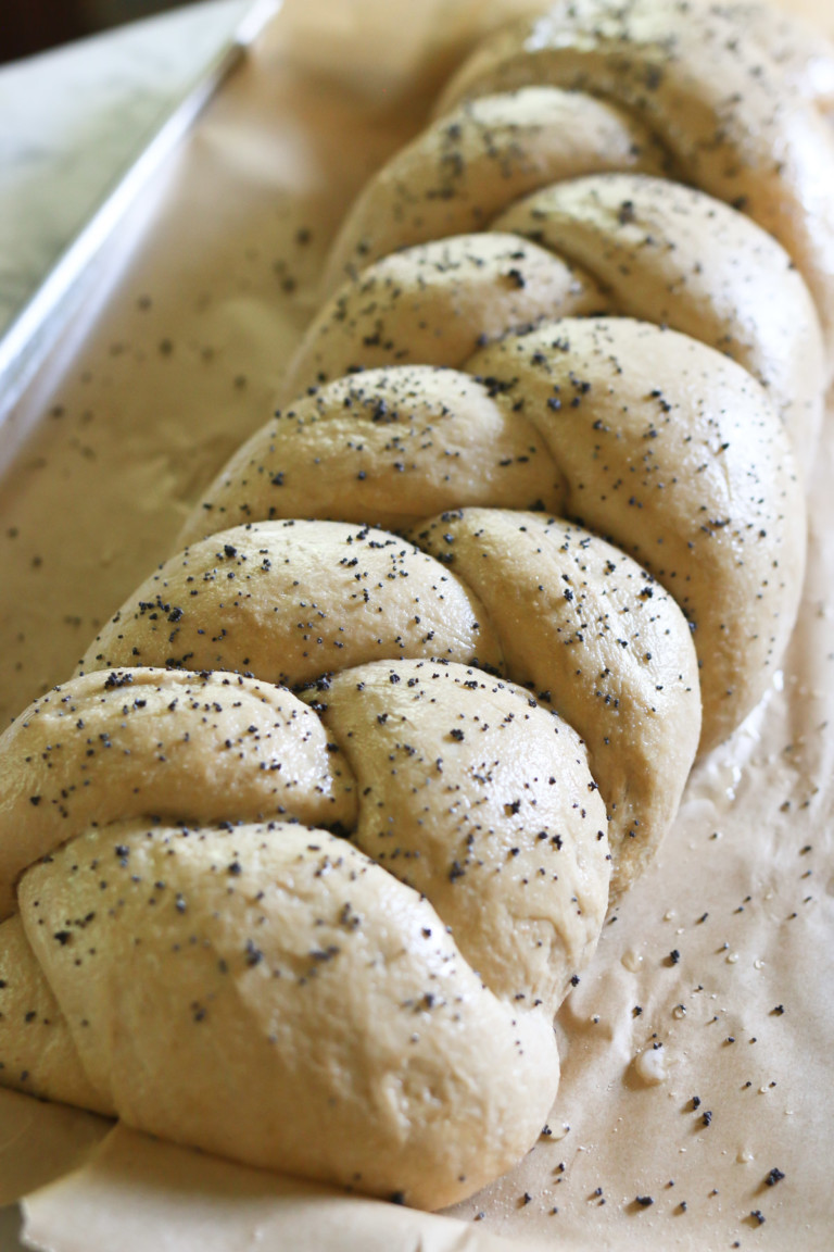 A freshly baked loaf of traditional challah bread is sprinkled with herbs
