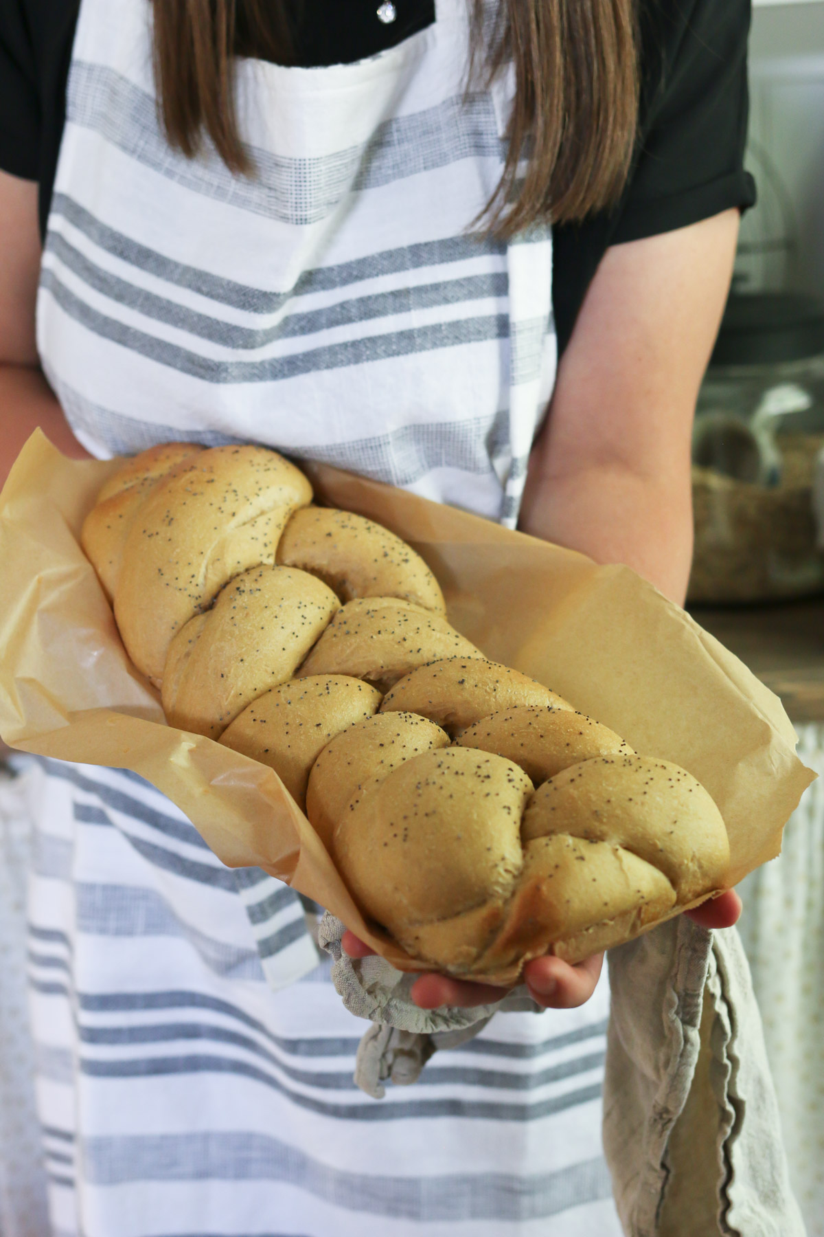 Someone holds up a loaf of braided challah bread that has been freshly baked