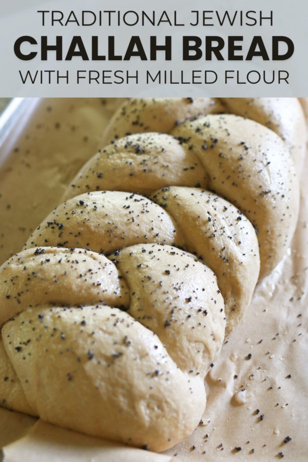 A braided loaf of challah bread is sprinkled with herbs