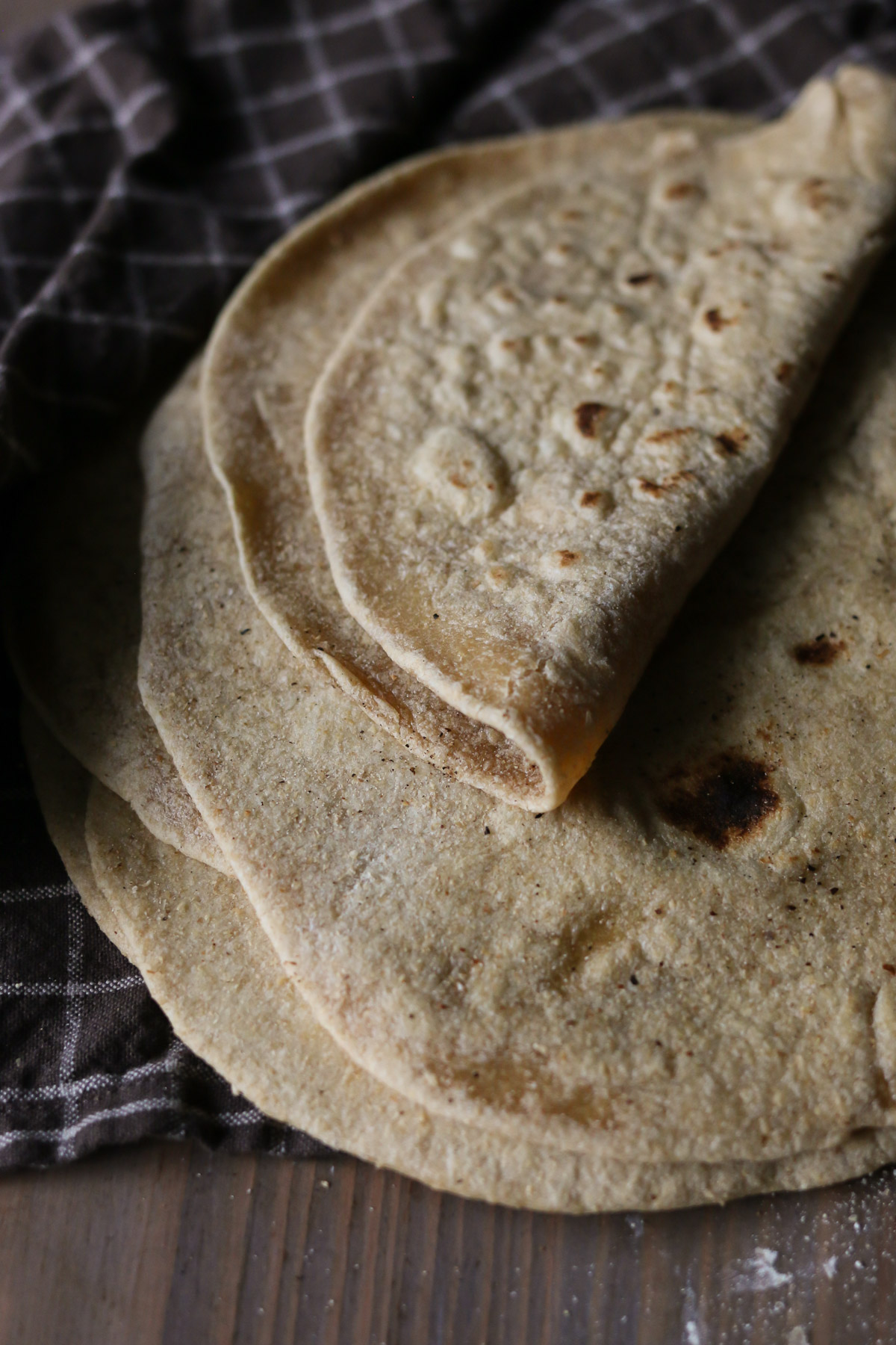 A pile of homemade freshly milled flour tortillas is displayed on a kitchen table