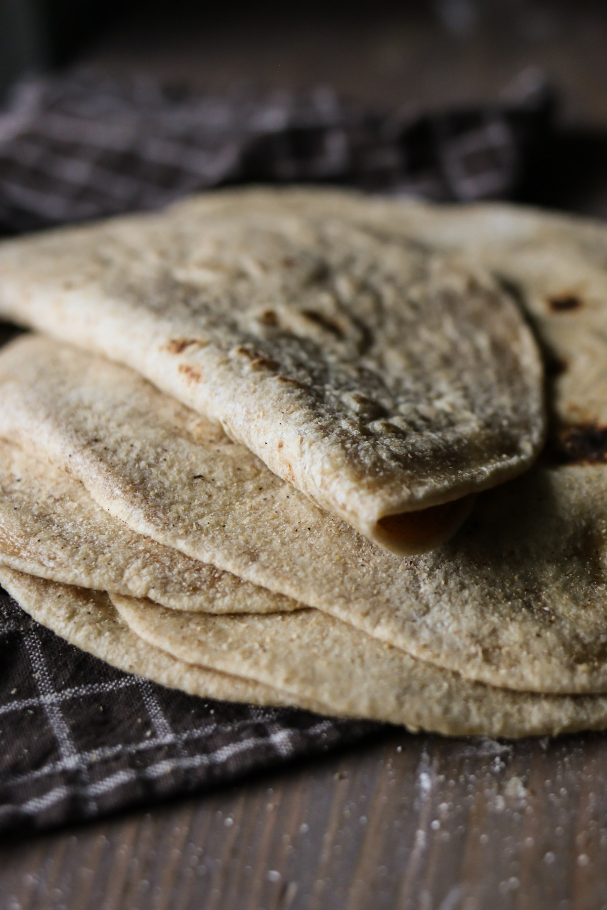 A pile of homemade tortillas is topped with a folded tortilla