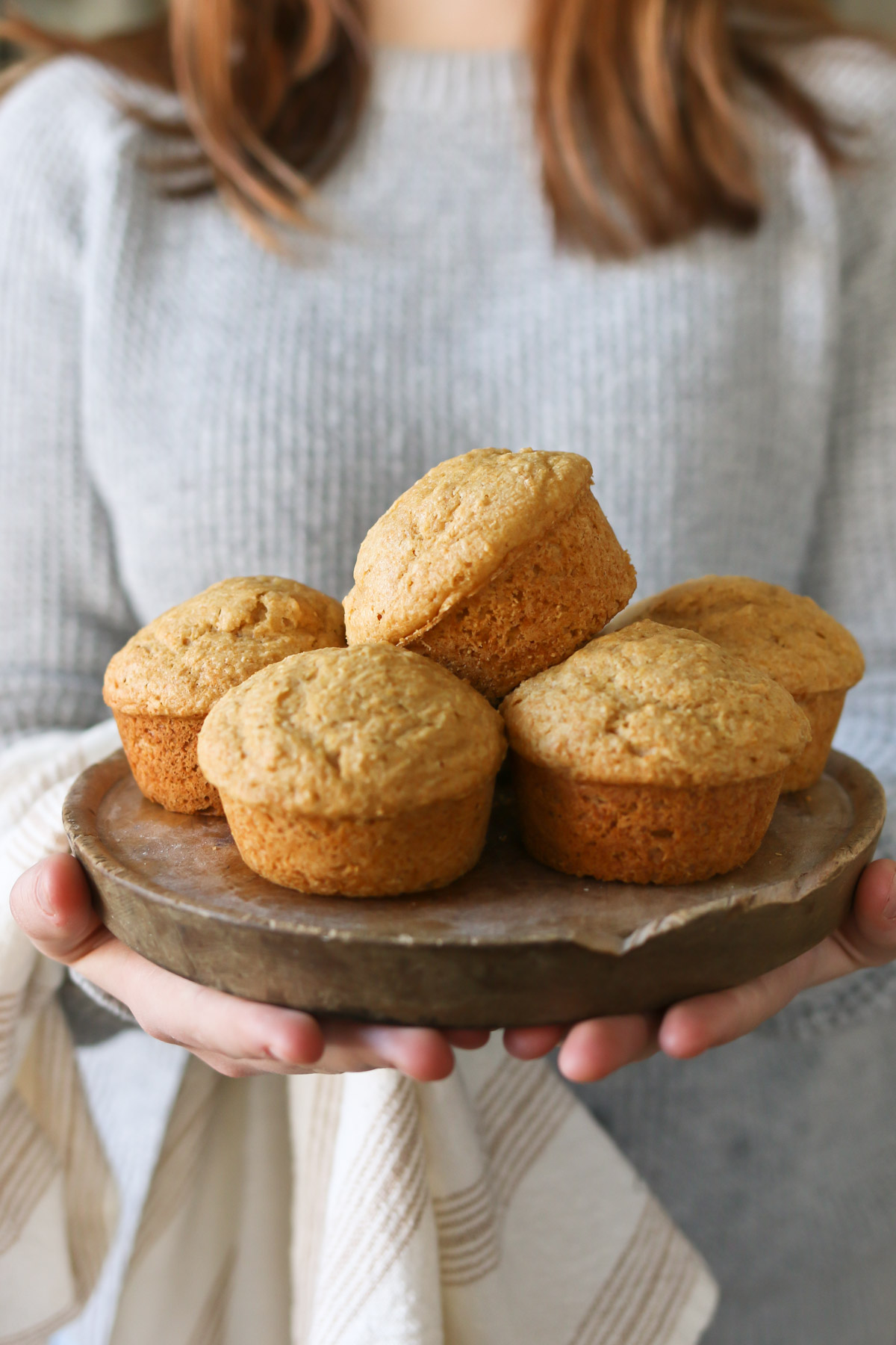 Someone holds a plate of simple basic muffins made from a freshly milled flour recipe