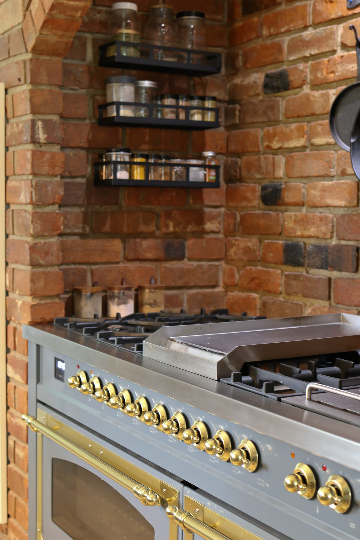 An Italian kitchen range has a red brick surround and racks for storing herbs and spices