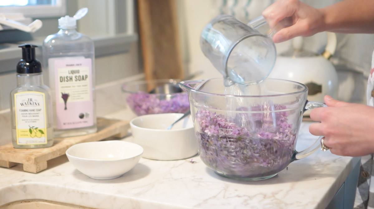 4 cups of boiling water are added to a bowl full of lilac petals to make lilac jelly
