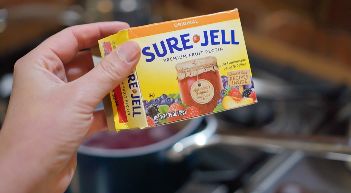 Someone holds a box of Sure Jell pectin that will be used to make lilac jelly