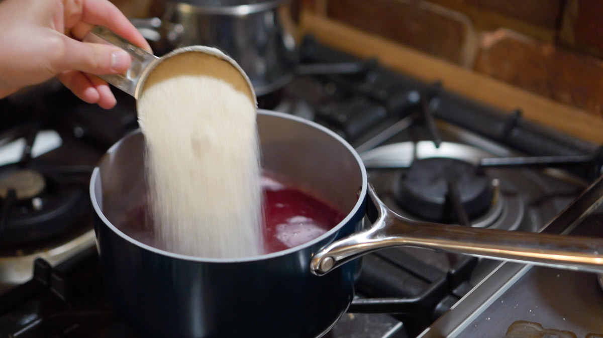 Sugar is added to a pot to make a lilac jelly recipe