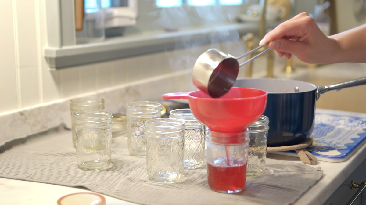 Hot lilac jelly is poured into a glass canning jar