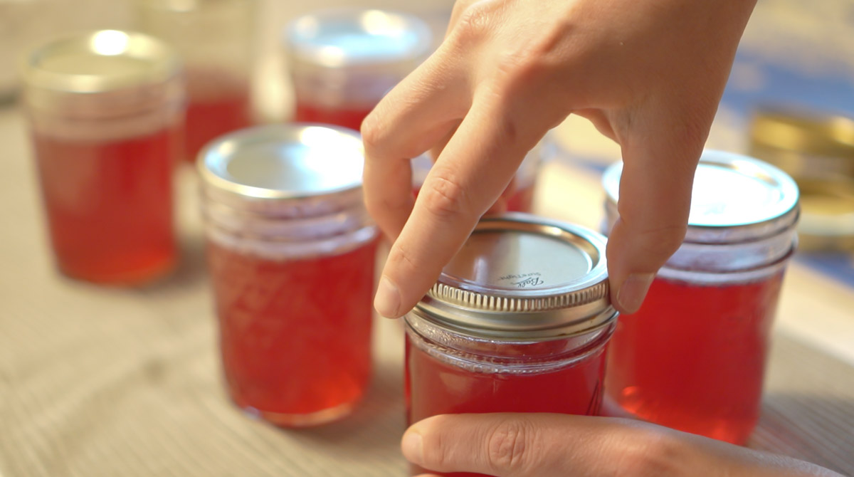 A metal lid is screwed onto a mason jar full of jell