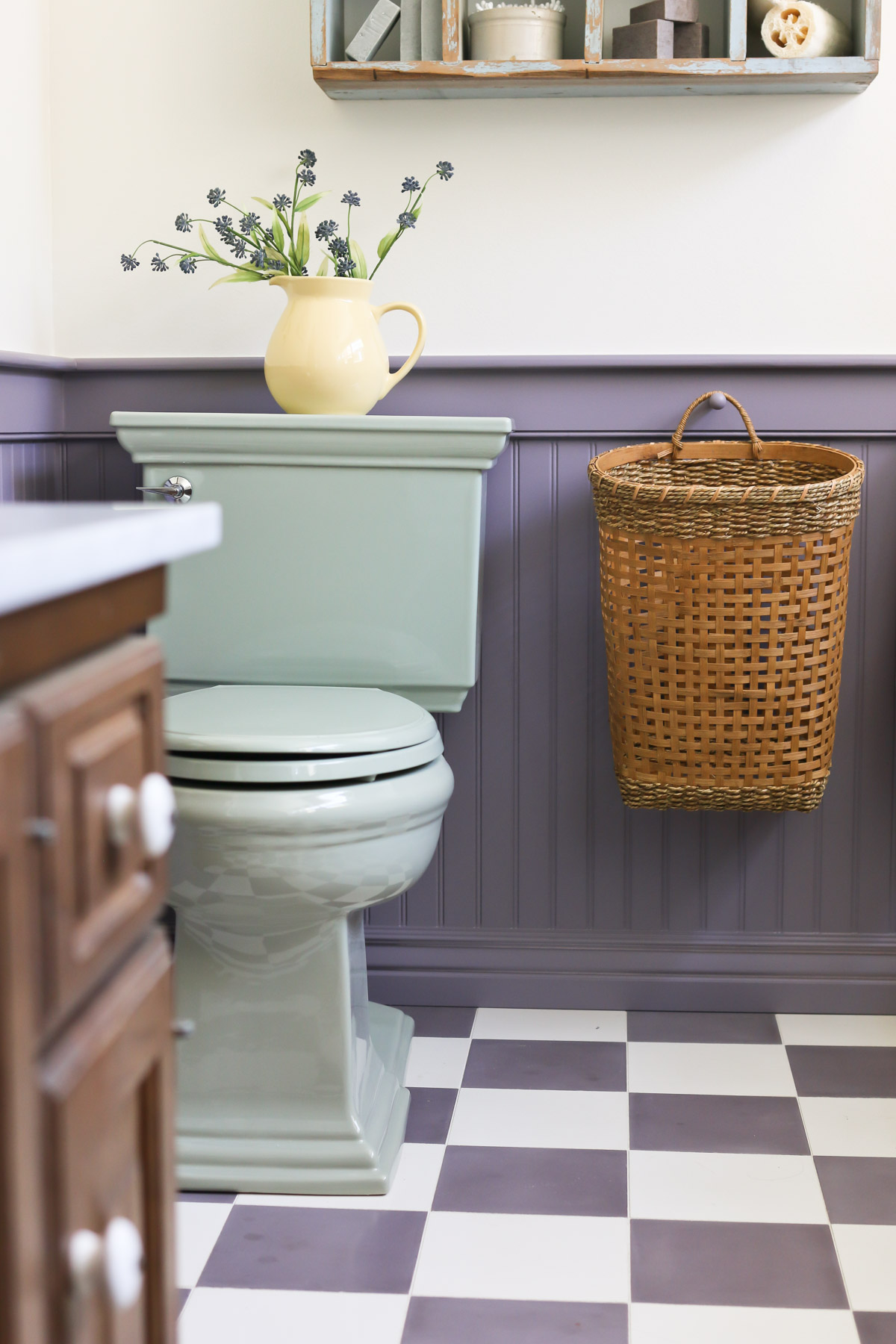 A green toilet sits in front of a purple bathroom wall with a beadboard wall treatment