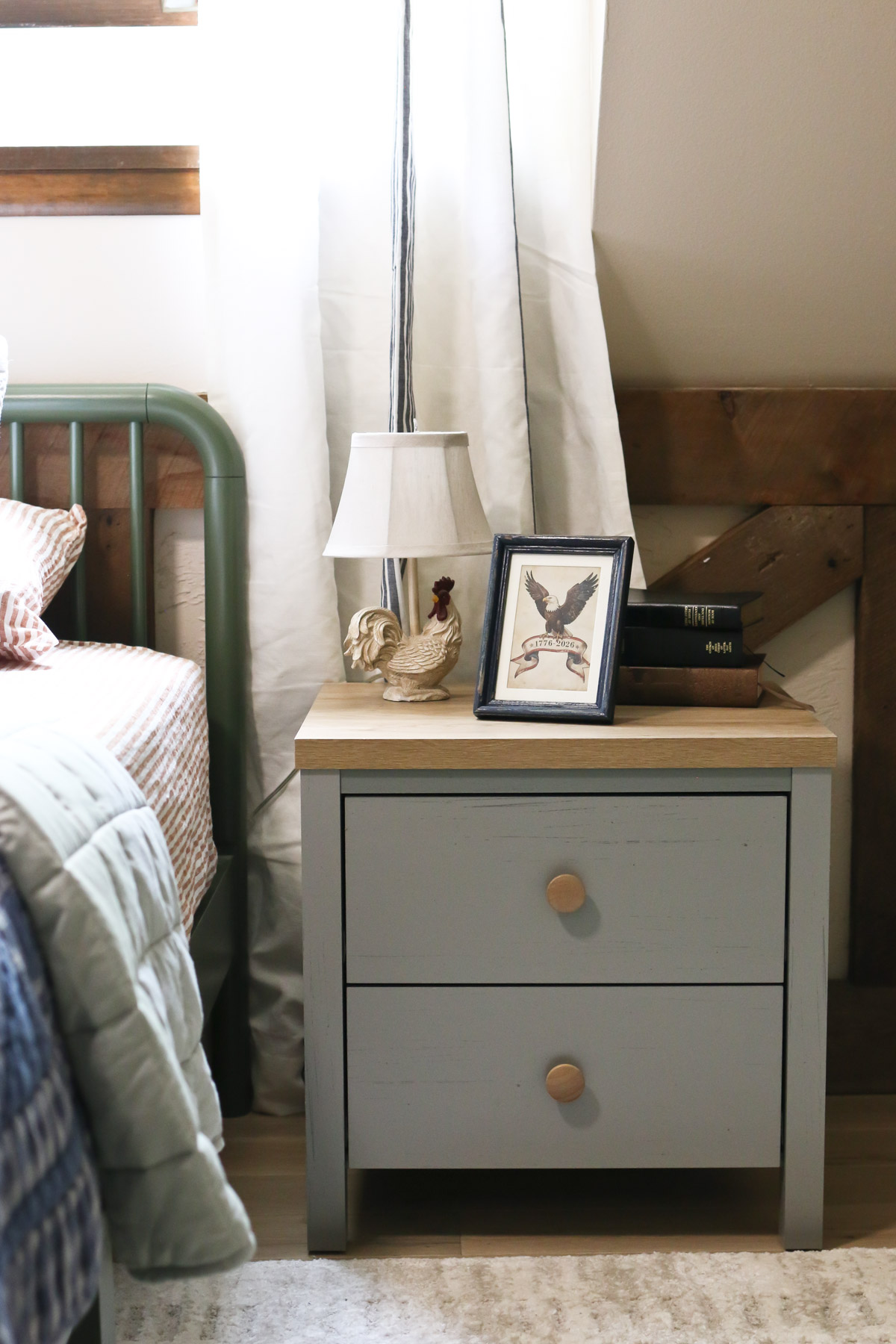 Vintage Americana style decorations are displayed on an end table next to a bed