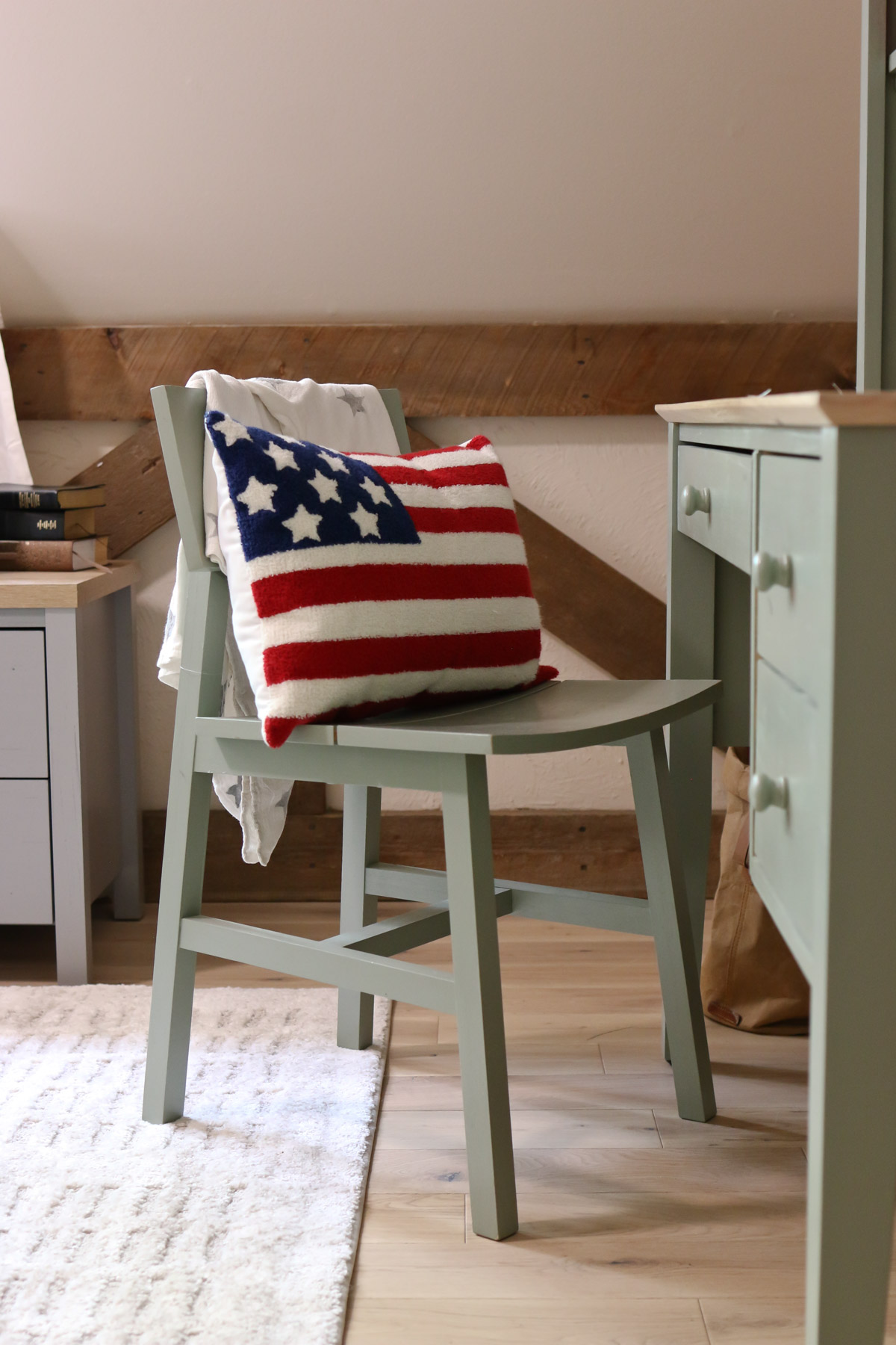 An American flag pillow rests on a desk chair in a bedroom