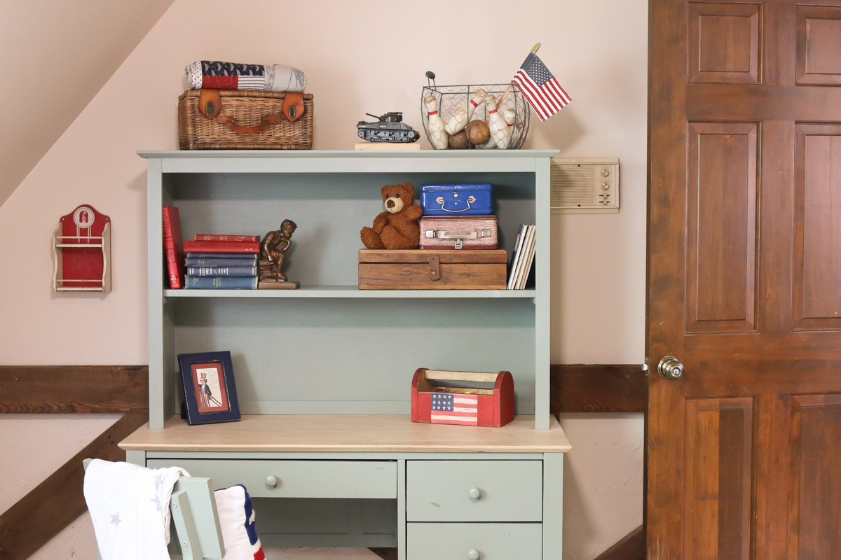 Vintage books and toys are displayed on a desk hutch as part of an Americana decorating idea