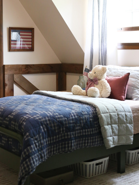 A bed in a cottage bedroom is decorated with vintage Americana themed decor