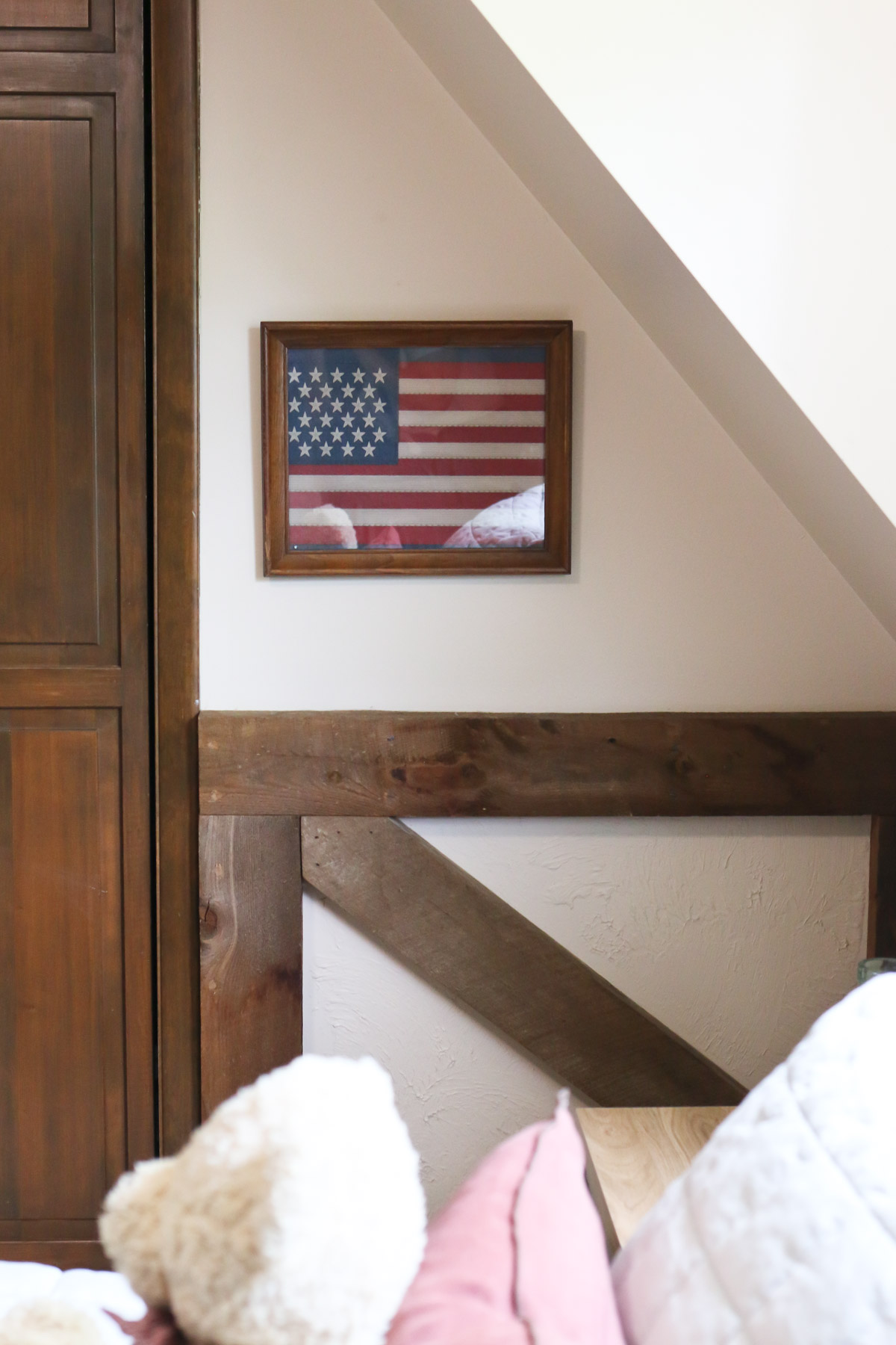 A framed American flag is hung on a bedroom wall