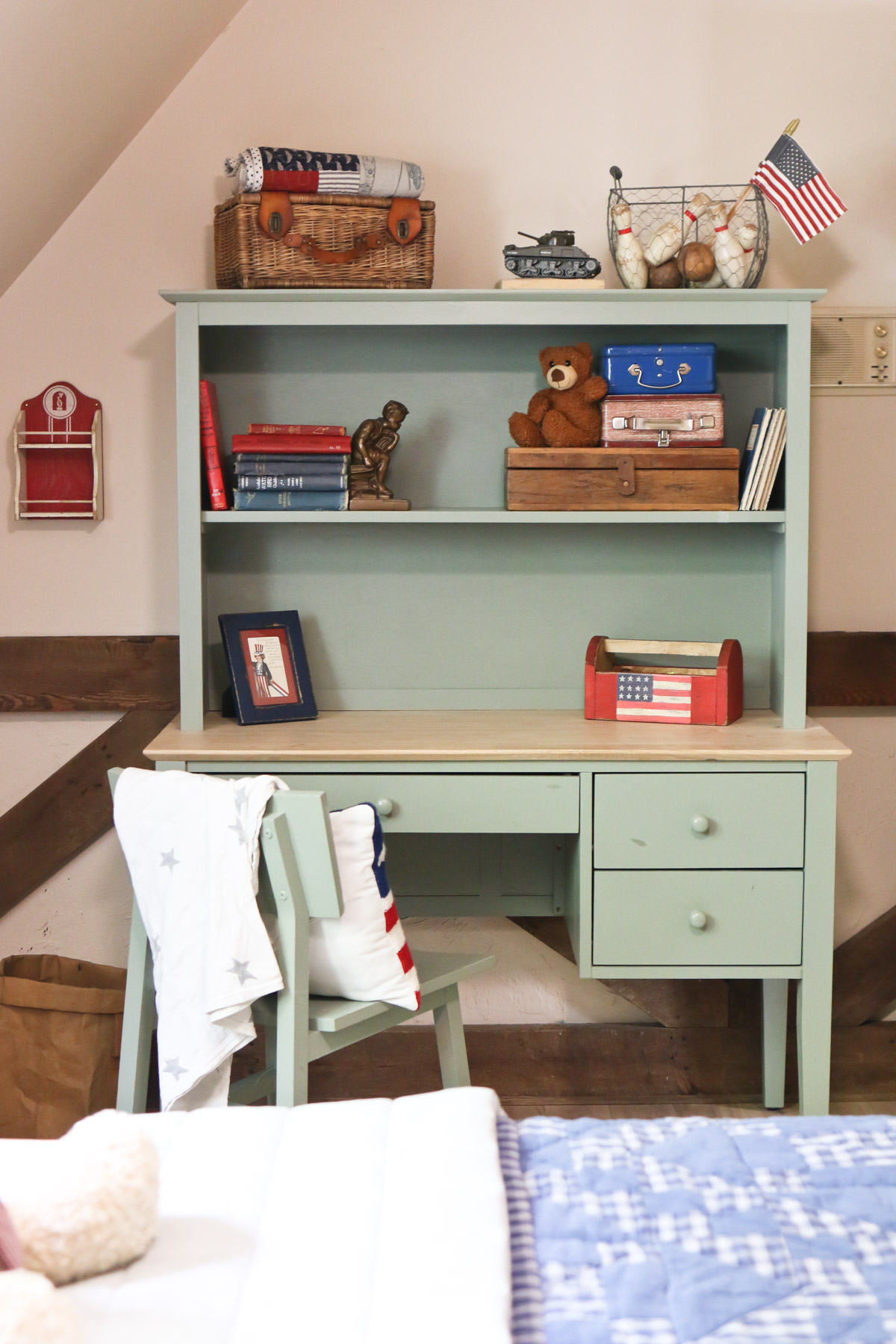 A view of a light green desk and hutch that are decorated with vintage Americana decor ideas