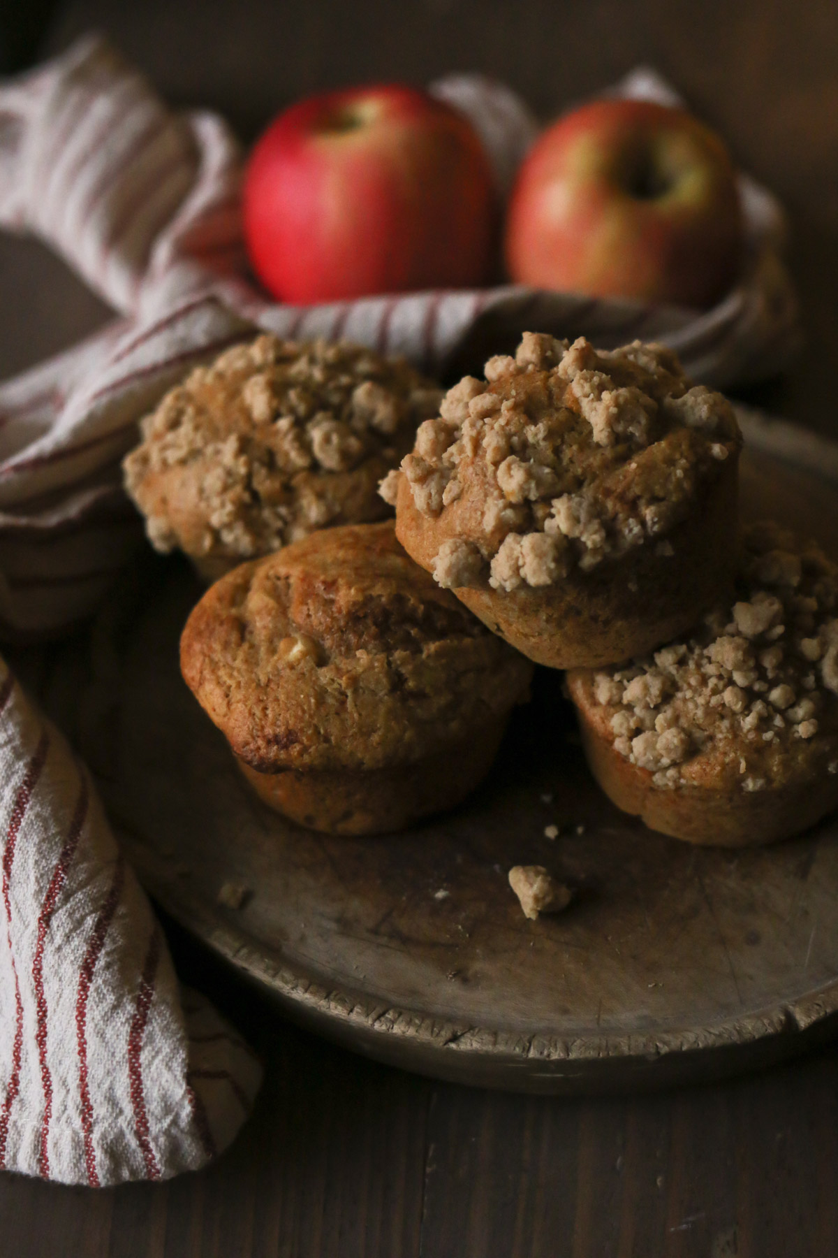 A plate hold apple cinnamon muffins next to a couple of ripe apples