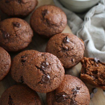 Several healthy chocolate muffins made with fresh milled flour are arranged on a cutting board