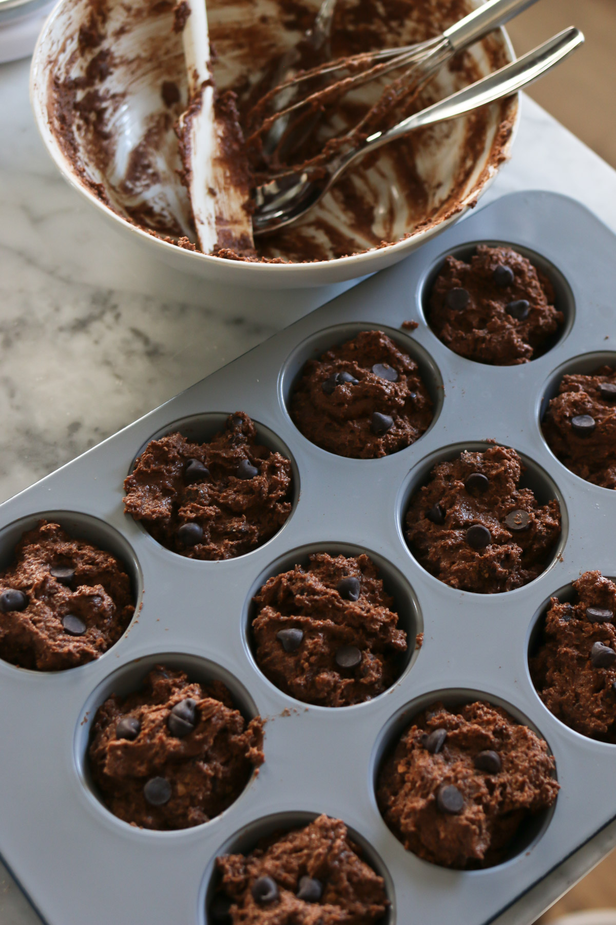 Healthy chocolate muffin batter fills each cup in a muffin tin