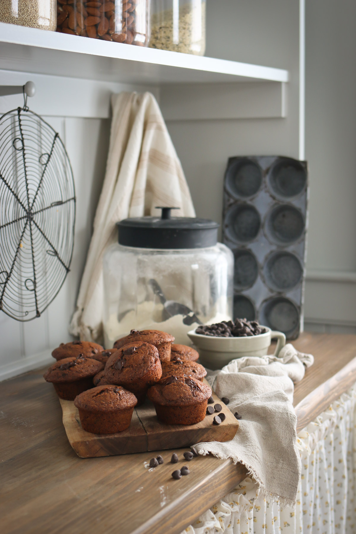 A jar of flour is displayed next to a bunch of healthy chocolate muffins from a fresh milled flour recipe