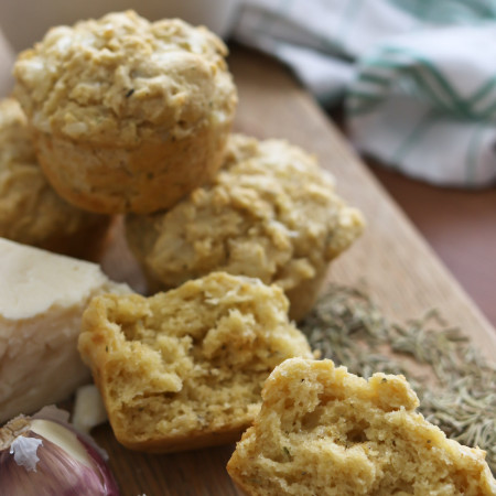 Savory herb and cheese muffins are arranged on a wooden cutting board