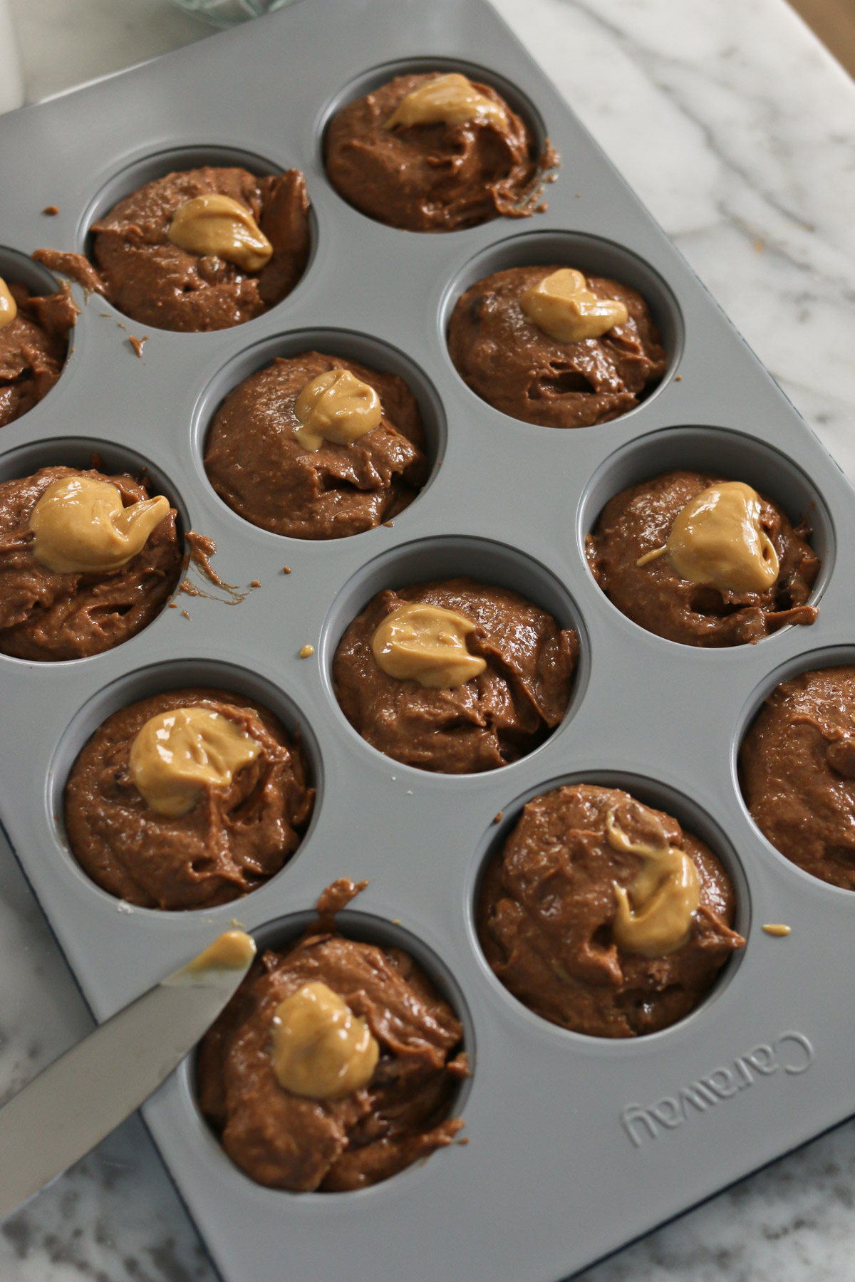 Dollops of peanut butter are placed on top of chocolate peanut butter muffins