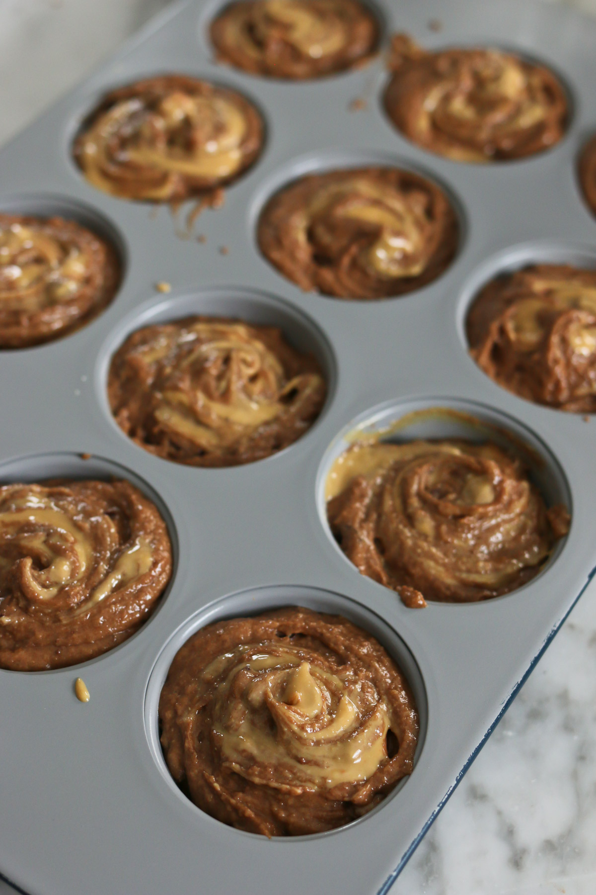 Muffin batter is placed in a muffin tin and ready to be baked