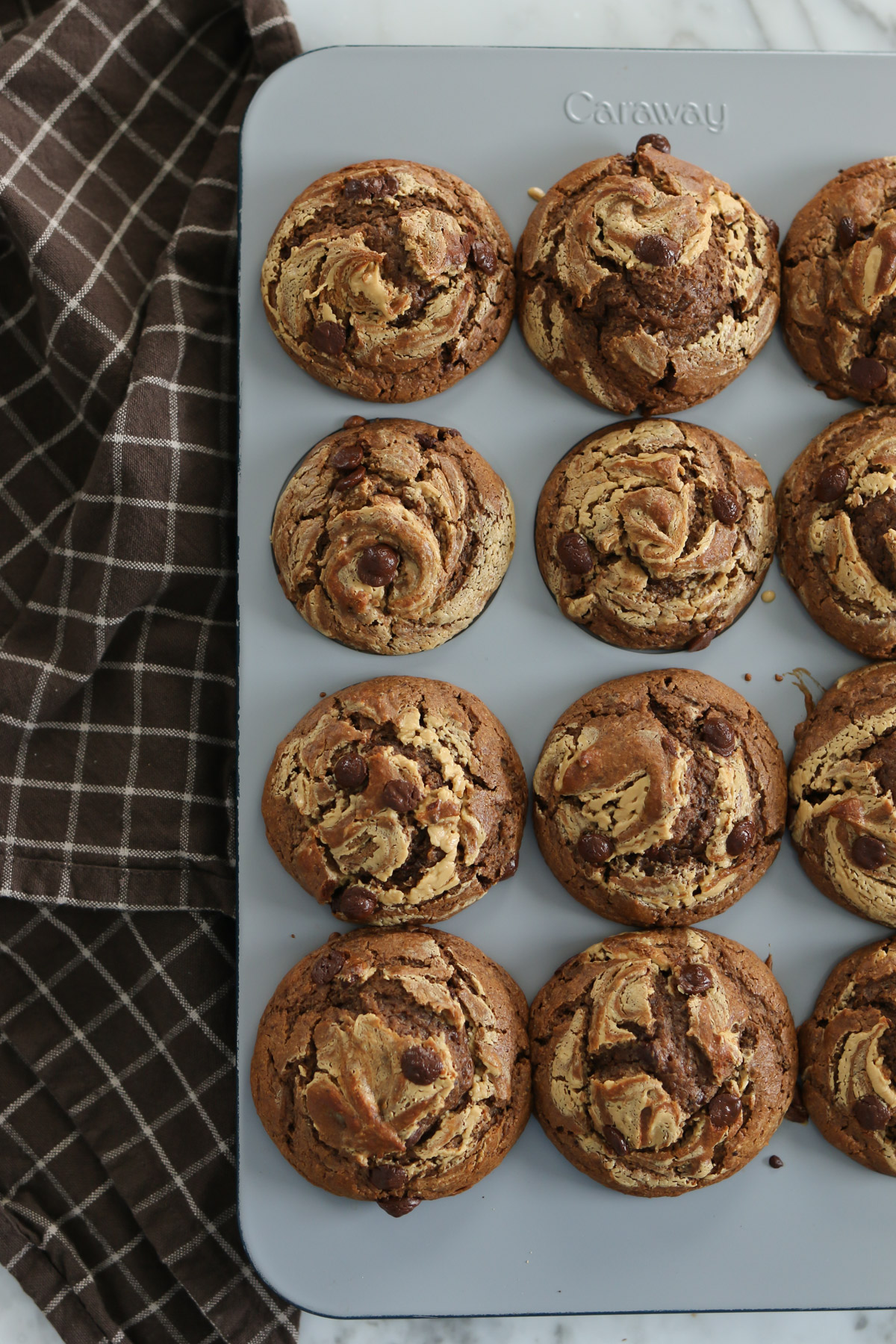 A muffin pan holds baked chocolate peanut butter muffins made with fresh milled flour